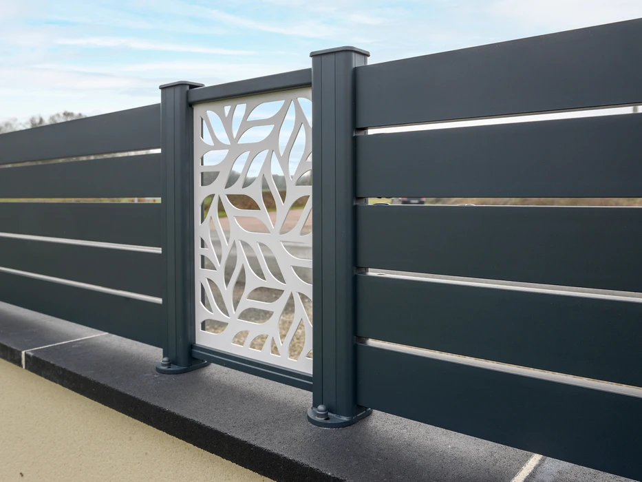 Scène extérieure résidentielle montrant une clôture moderne installée le long d'une allée pavée claire