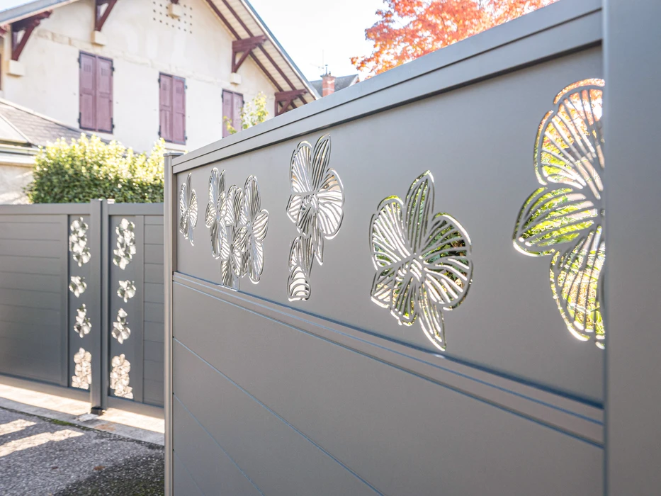 Scène extérieure résidentielle montrant une clôture moderne installée le long d'une allée pavée claire