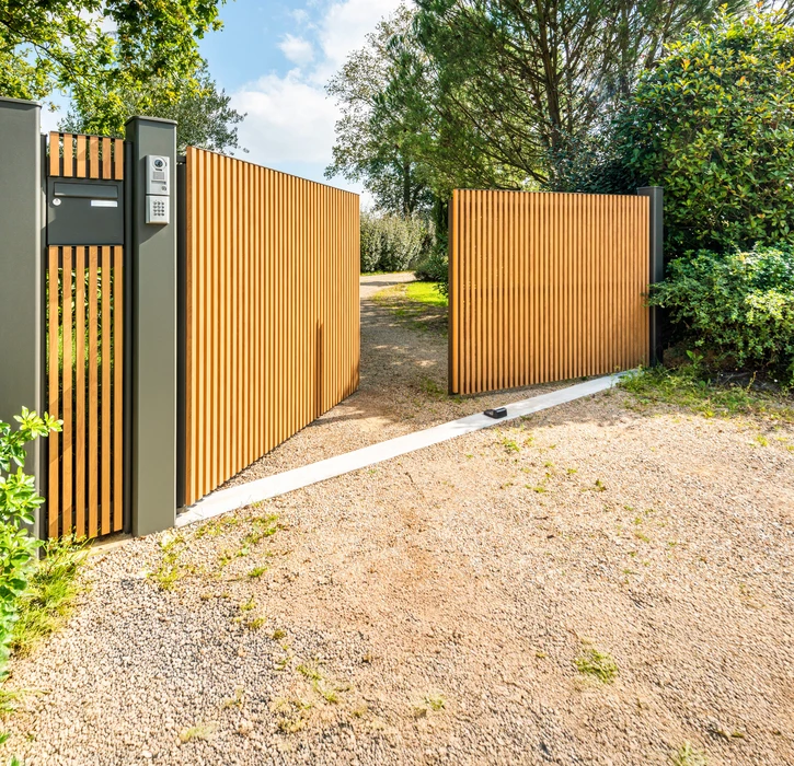 Scène extérieure résidentielle montrant une clôture moderne installée le long d'une allée pavée claire
